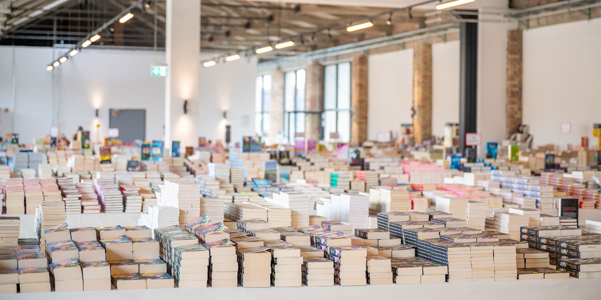 Eine Aufnahme des Bücherzirkus Prora auf Rügen. Tische voller Büchertstapel.